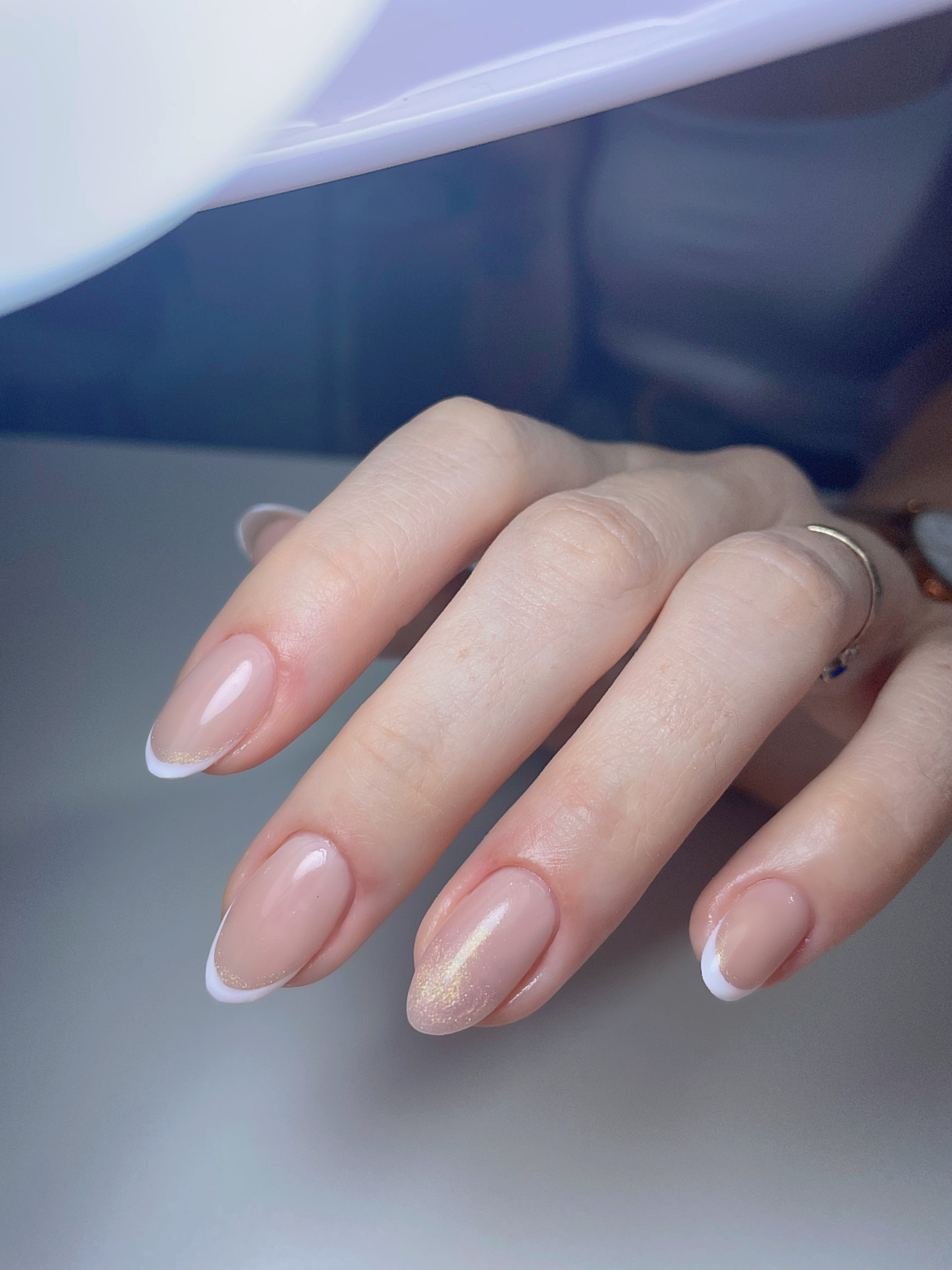 Close de unhas naturais com francesinha e brilho dourado