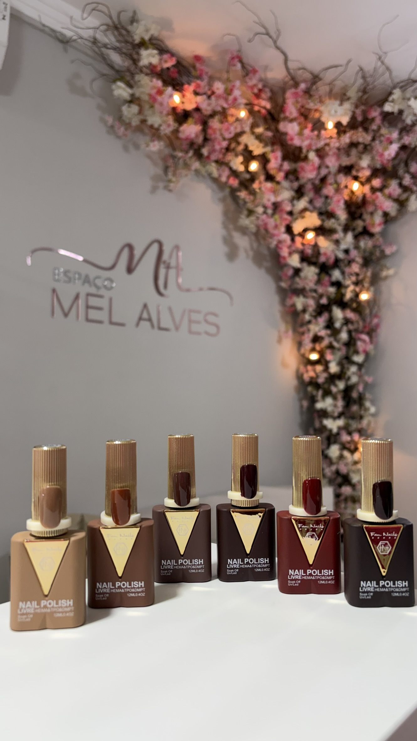 Esmaltes em gel em frente à parede com a marca Espaço Mel Alves